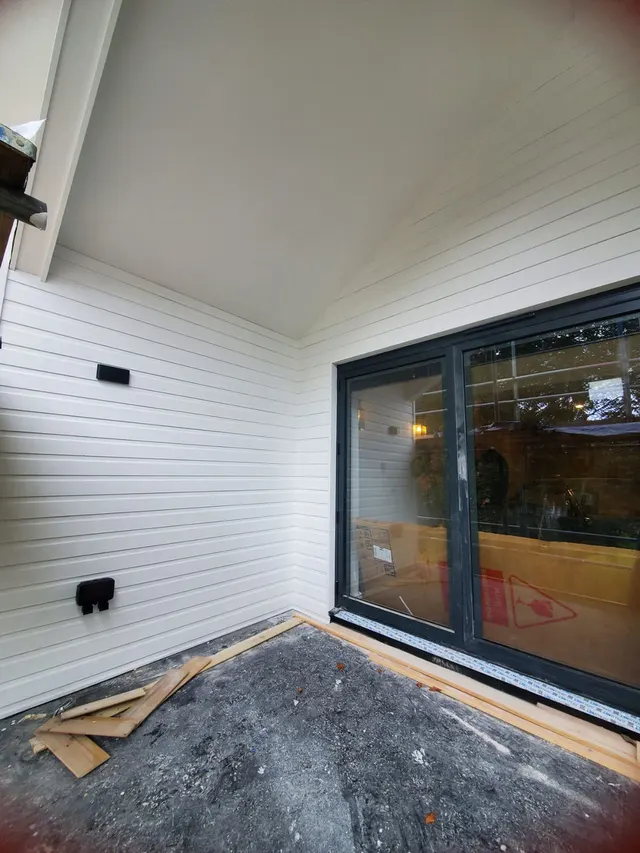 Exterior cladding installation and patio-door preparation in progress