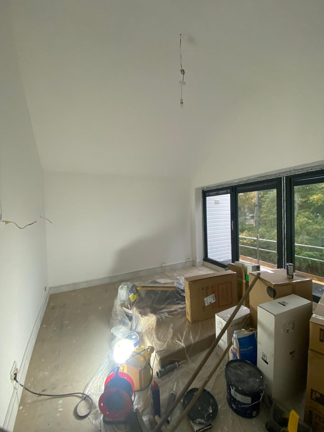 Room with prepared walls and protected furniture before finishing work