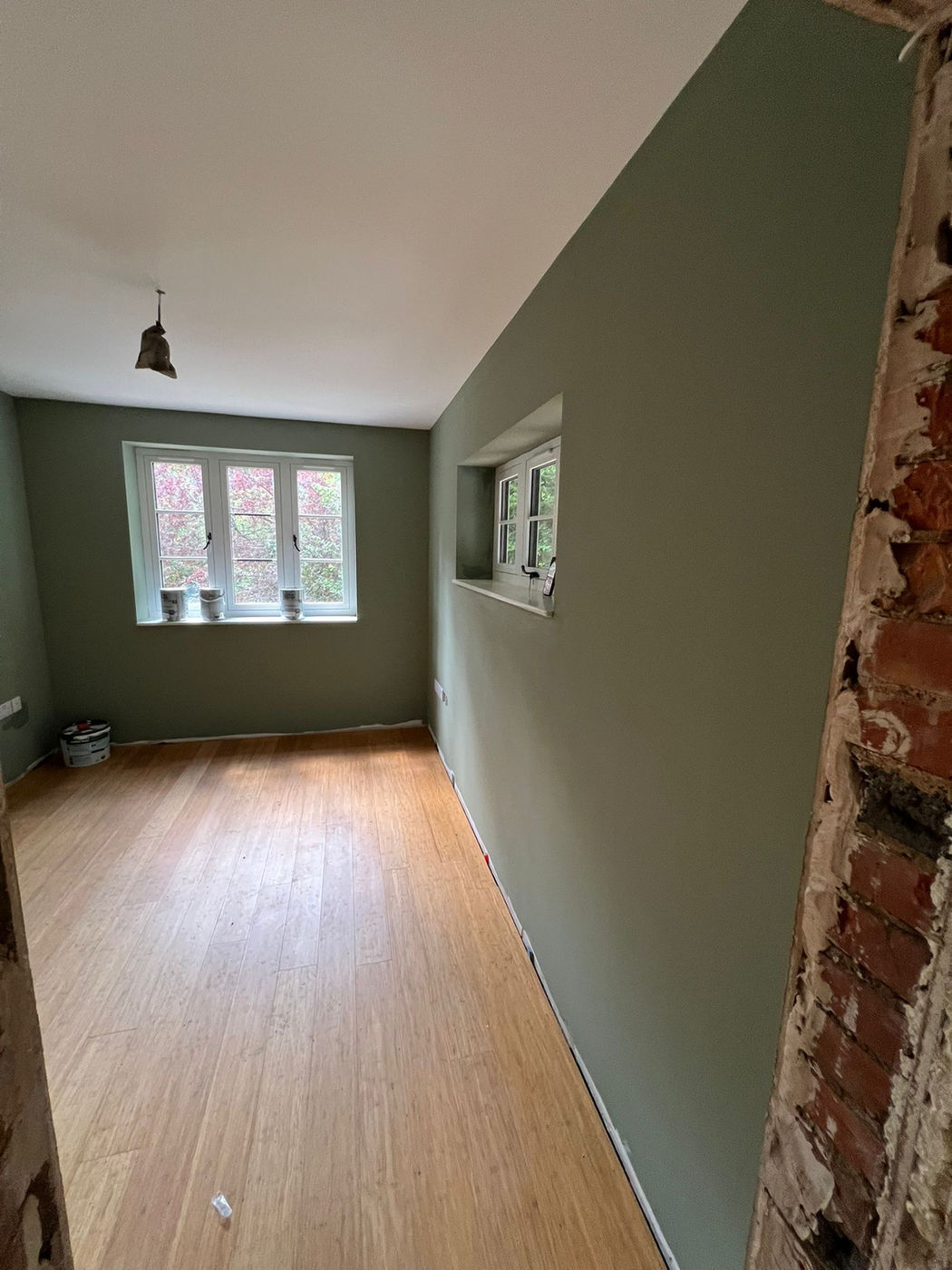 Room with green painted walls and wood flooring after decorating work